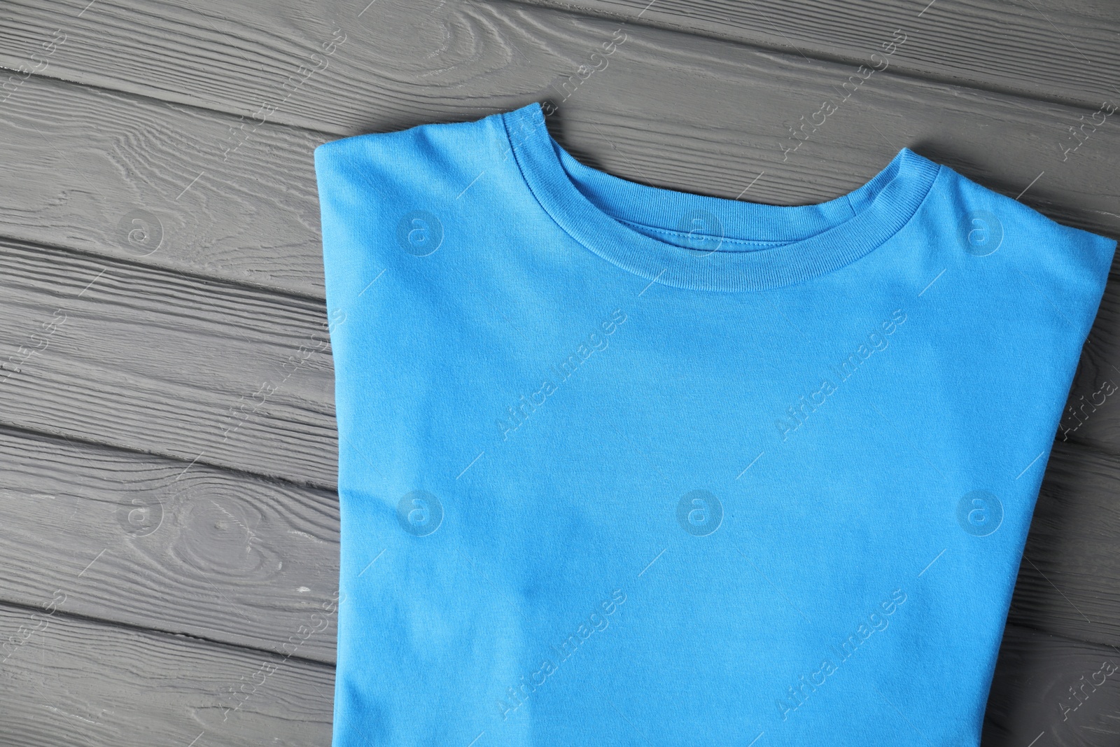 Photo of Light blue t-shirt on grey wooden table, top view. Mockup for design