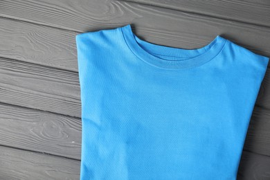 Photo of Light blue t-shirt on grey wooden table, top view. Mockup for design