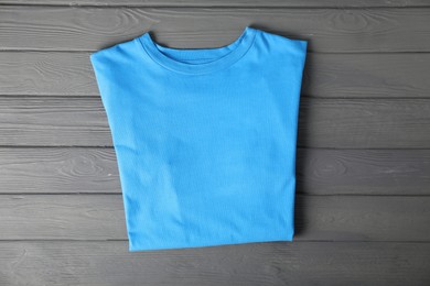 Photo of Light blue t-shirt on grey wooden table, top view. Mockup for design