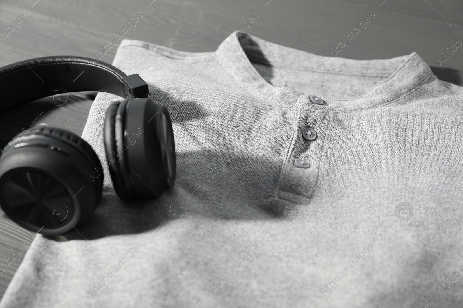 Photo of T-shirt and headphones on grey wooden table, closeup. Mockup for design