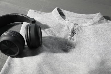 Photo of T-shirt and headphones on grey wooden table, closeup. Mockup for design