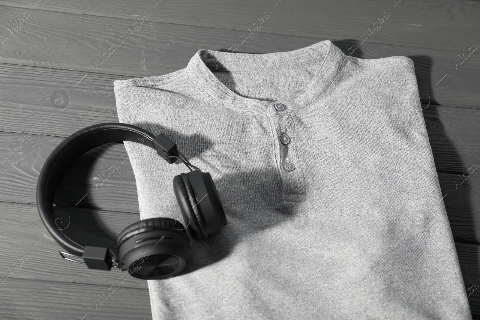 Photo of T-shirt and headphones on grey wooden table, above view. Mockup for design