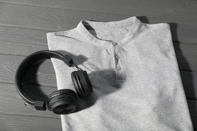 Photo of T-shirt and headphones on grey wooden table, above view. Mockup for design