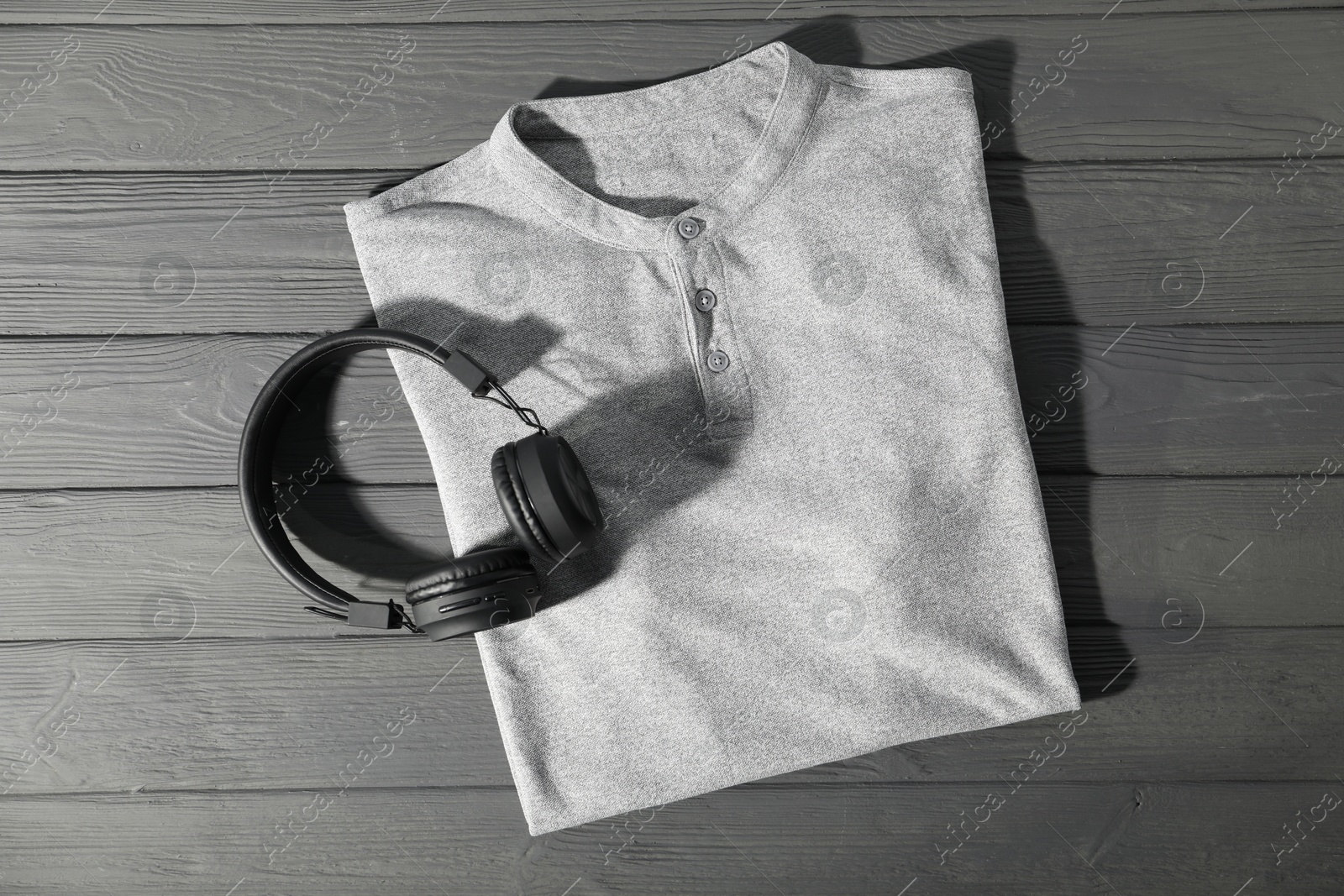 Photo of T-shirt and headphones on grey wooden table, top view. Mockup for design
