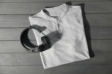 Photo of T-shirt and headphones on grey wooden table, top view. Mockup for design