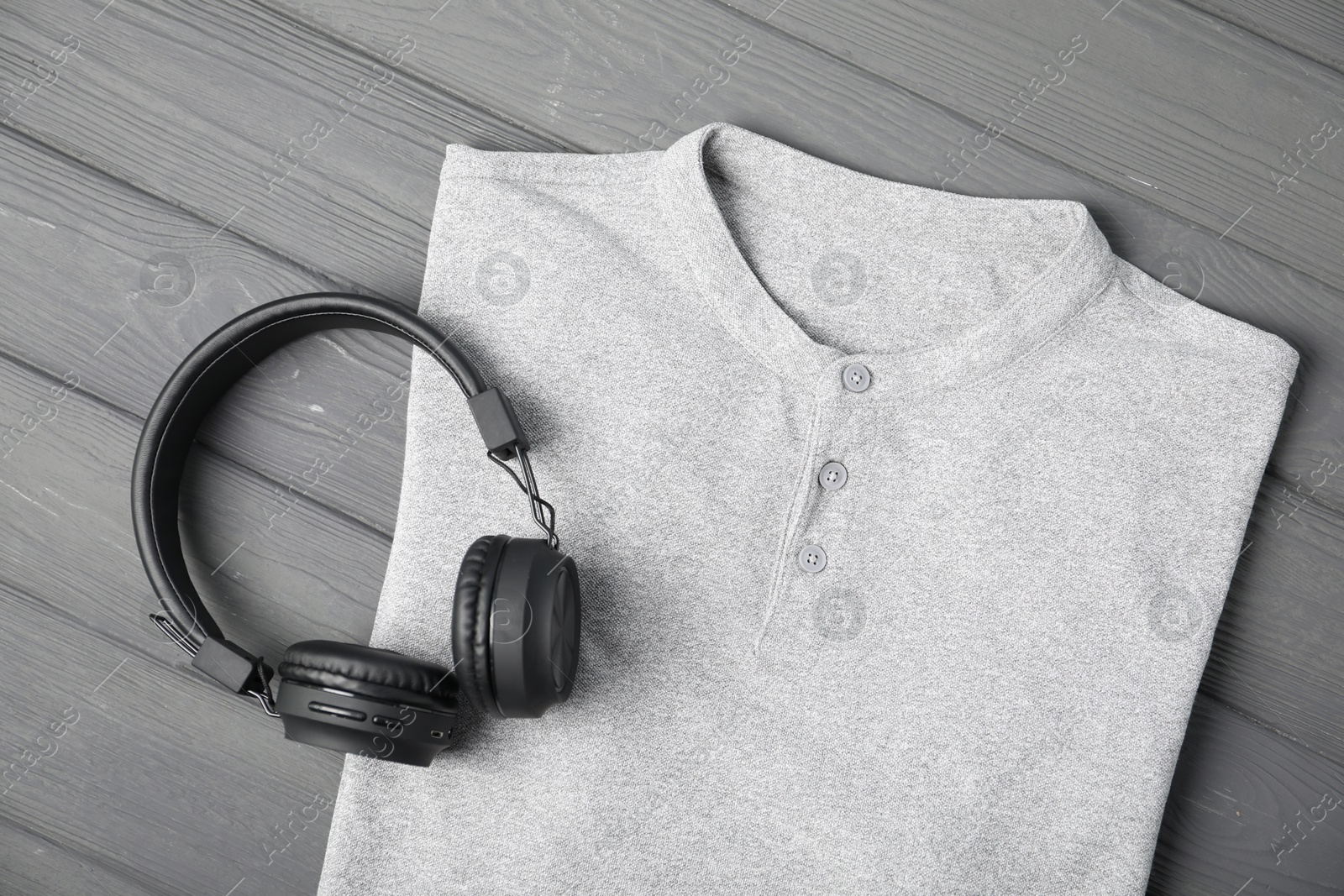 Photo of T-shirt and headphones on grey wooden table, top view. Mockup for design