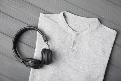 Photo of T-shirt and headphones on grey wooden table, top view. Mockup for design