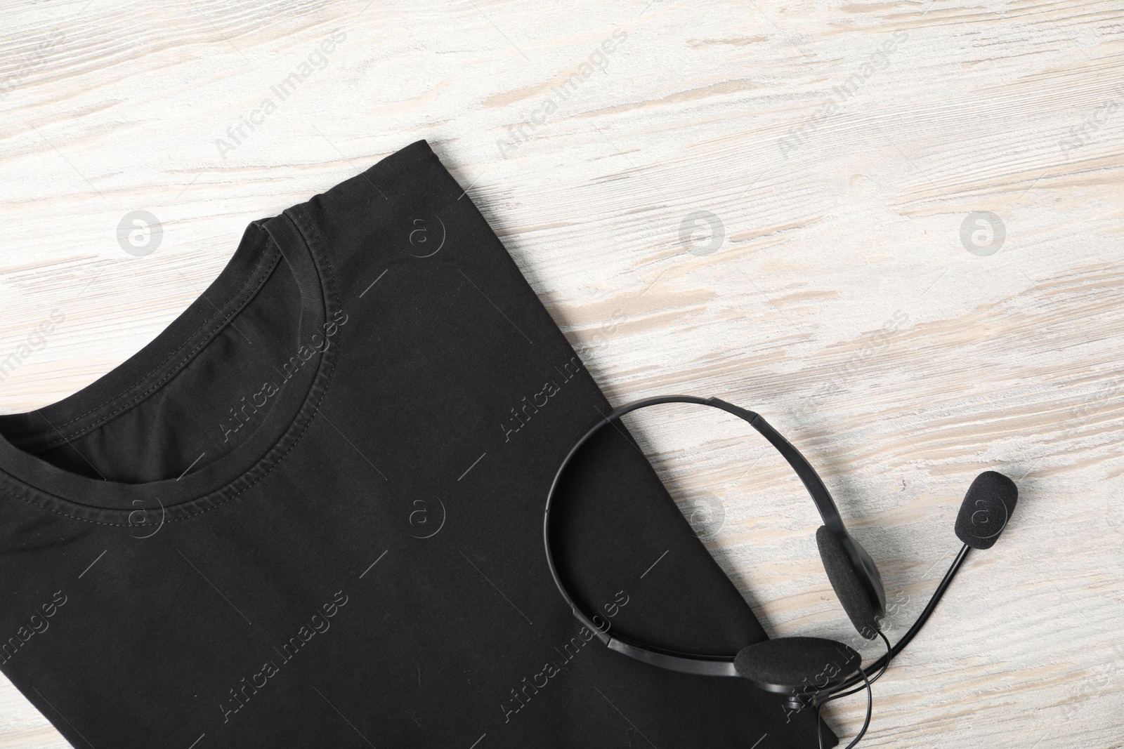 Photo of Black t-shirt and headset on wooden table, top view. Mockup for design