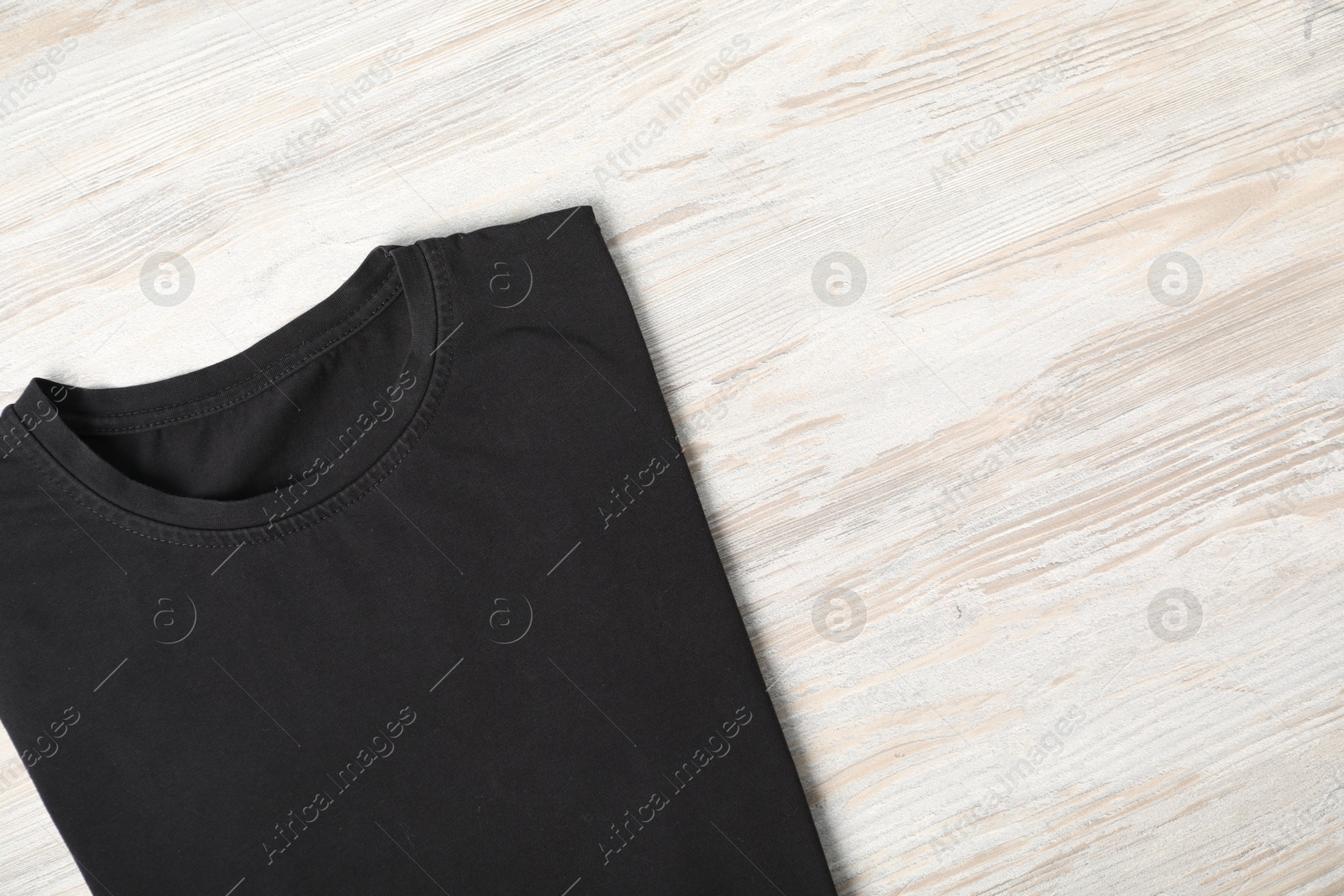 Photo of Black t-shirt on wooden table, top view. Mockup for design