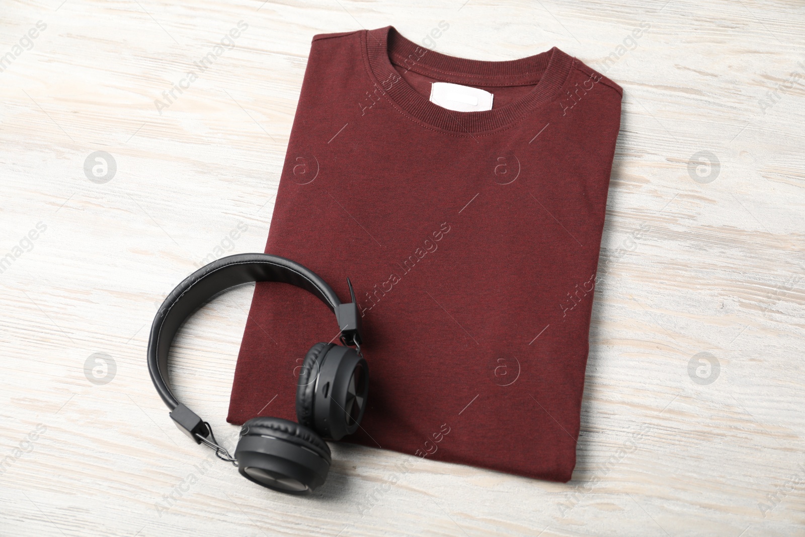 Photo of Brown t-shirt and headphones on wooden table, top view. Mockup for design