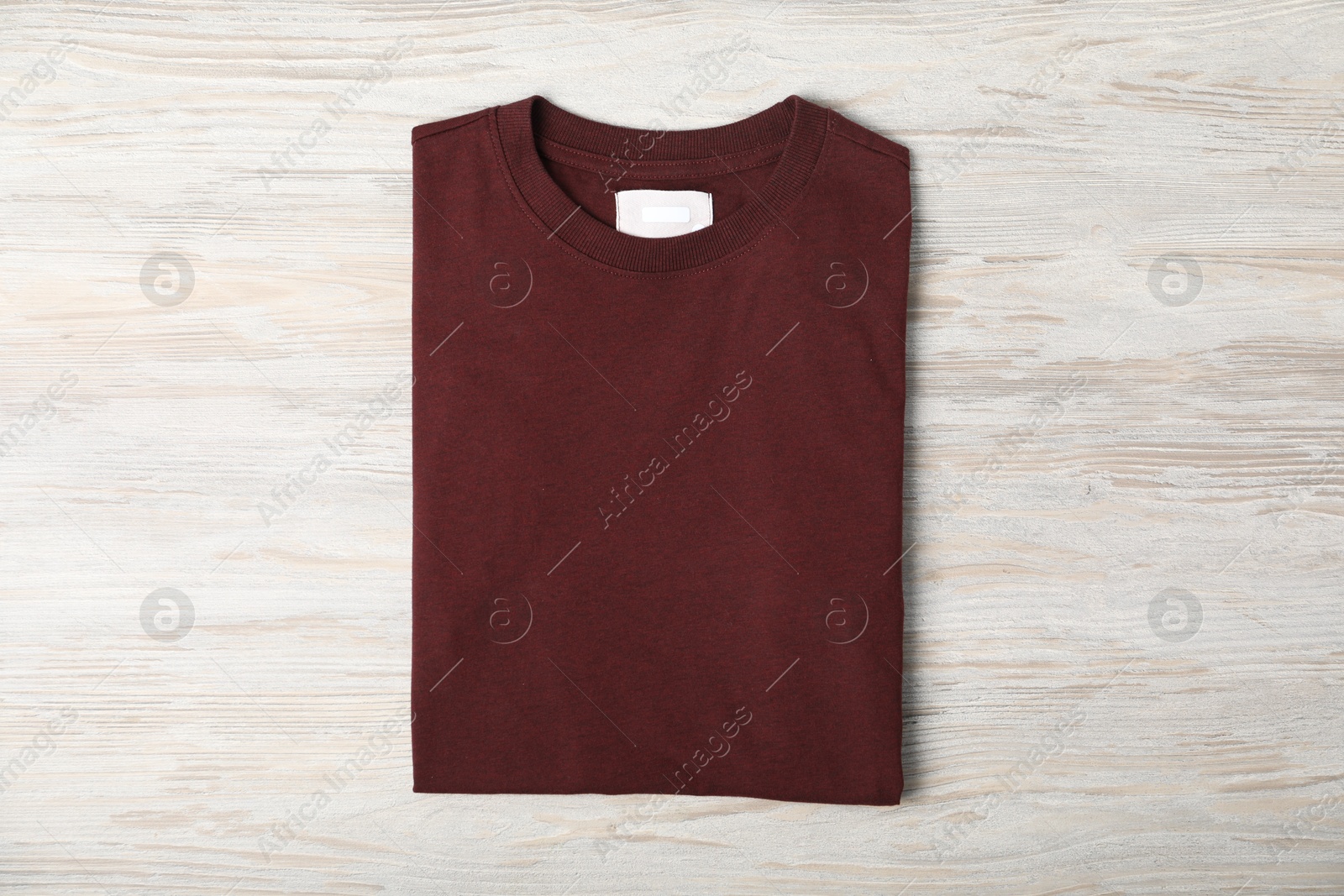 Photo of Brown t-shirt on wooden table, top view. Mockup for design