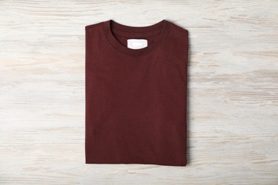 Photo of Brown t-shirt on wooden table, top view. Mockup for design
