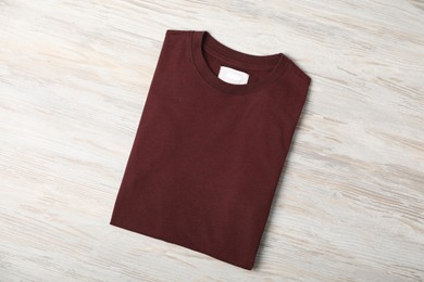 Photo of Brown t-shirt on wooden table, top view. Mockup for design