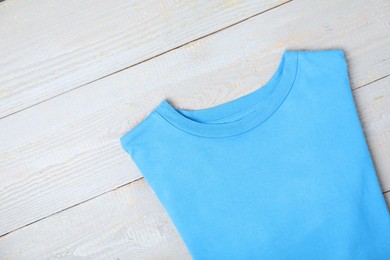 Photo of Light blue t-shirt on wooden table, top view. Mockup for design
