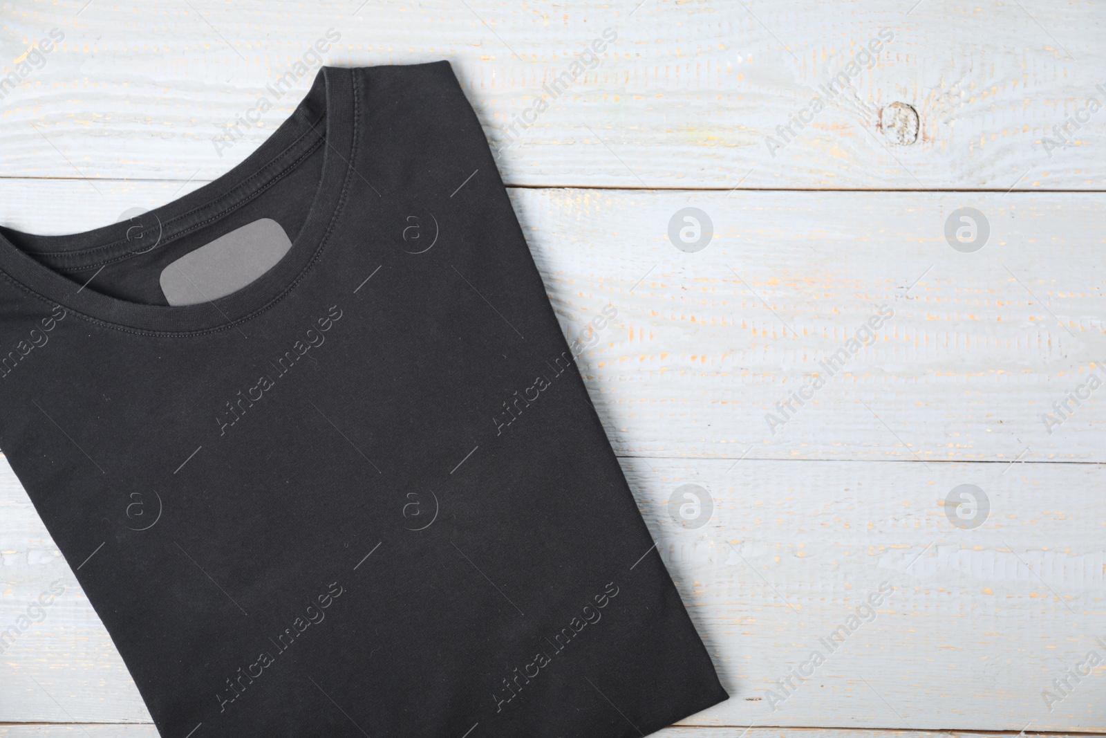 Photo of Black t-shirt on wooden table, top view. Mockup for design