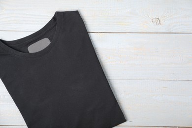 Photo of Black t-shirt on wooden table, top view. Mockup for design