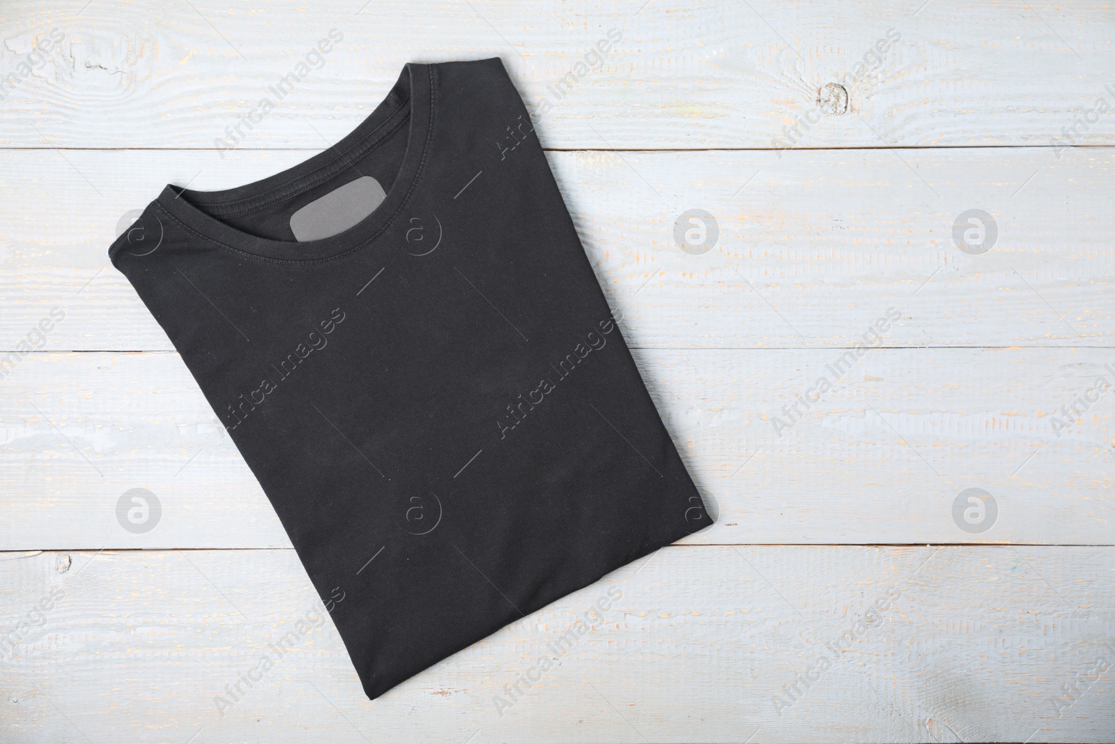Photo of Black t-shirt on wooden table, top view. Mockup for design