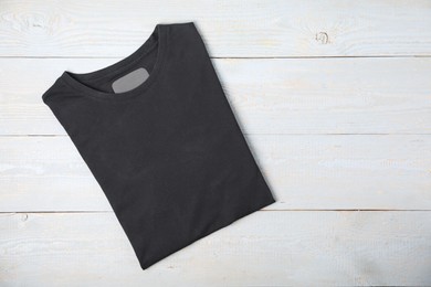 Photo of Black t-shirt on wooden table, top view. Mockup for design