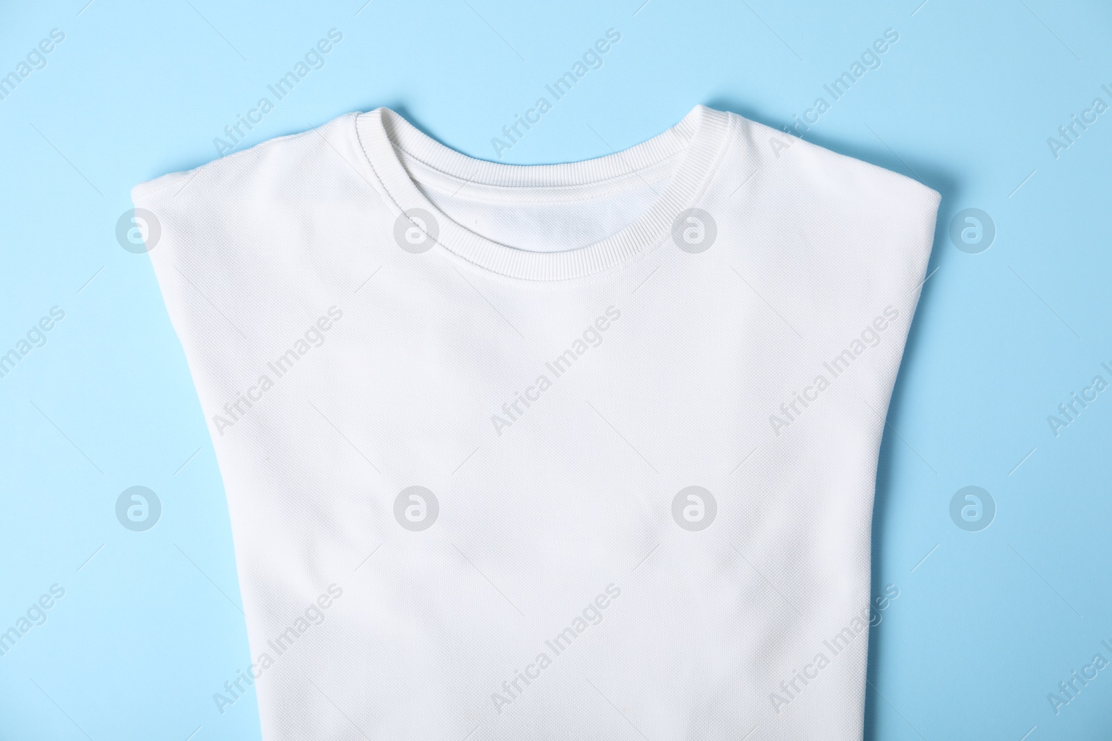 Photo of White t-shirt on light blue background, top view. Mockup for design