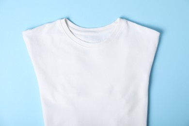 Photo of White t-shirt on light blue background, top view. Mockup for design