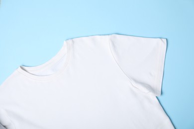 Photo of White t-shirt on light blue background, top view. Mockup for design