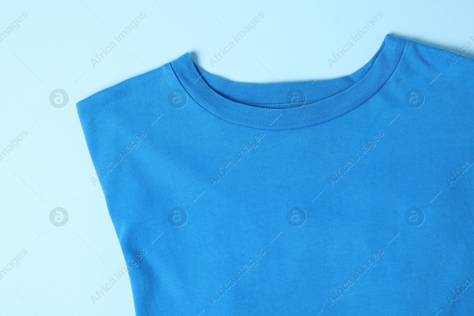 Photo of T-shirt on light blue background, top view. Mockup for design