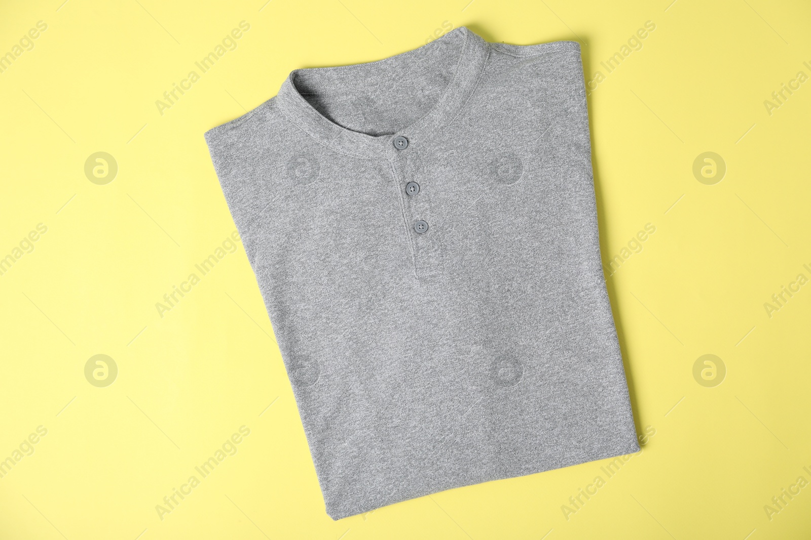 Photo of Grey t-shirt on yellow background, top view. Mockup for design