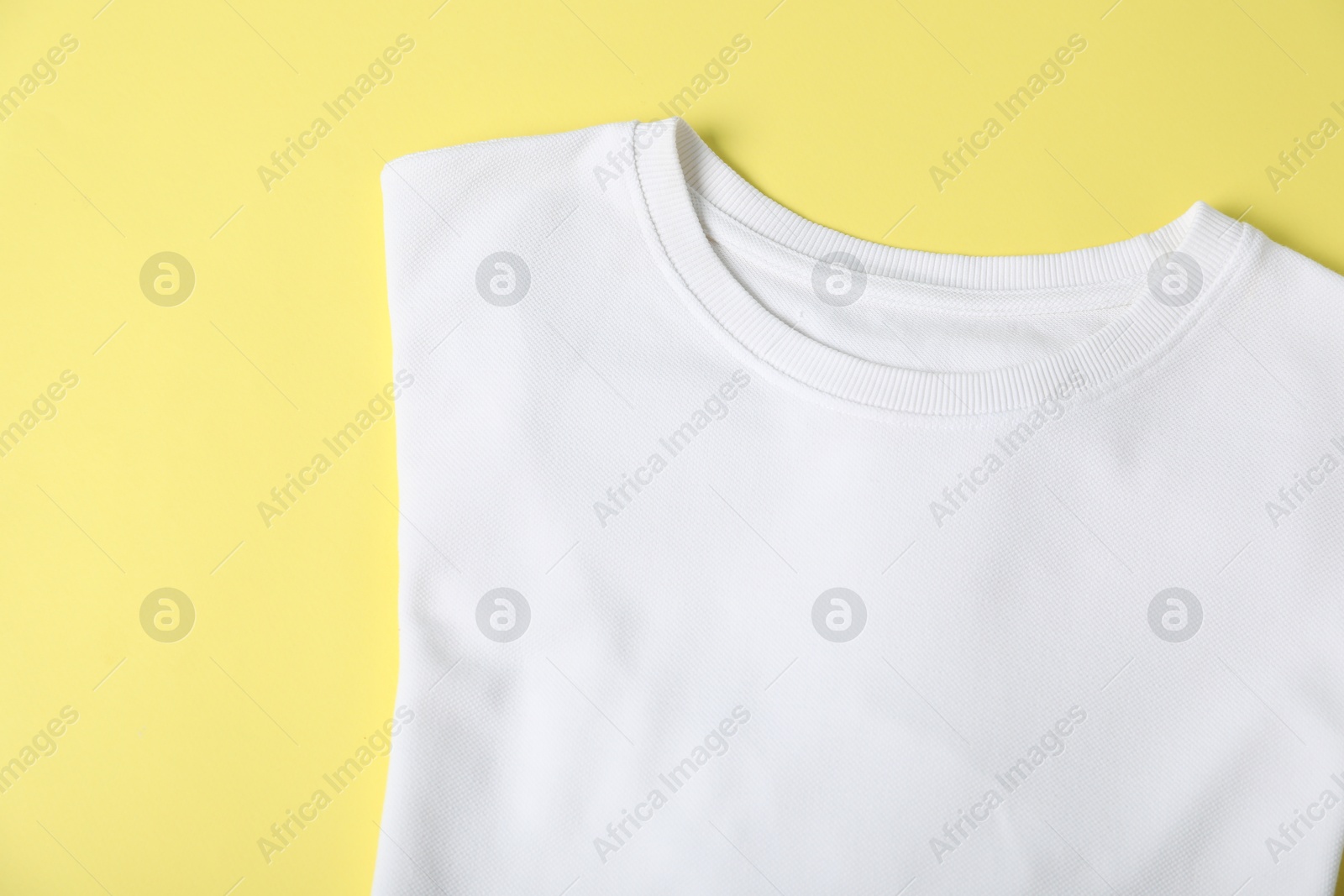 Photo of White t-shirt on yellow background, top view. Mockup for design