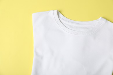 Photo of White t-shirt on yellow background, top view. Mockup for design