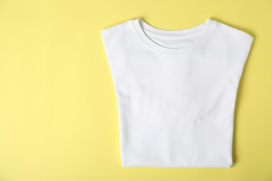 Photo of White t-shirt on yellow background, top view. Mockup for design