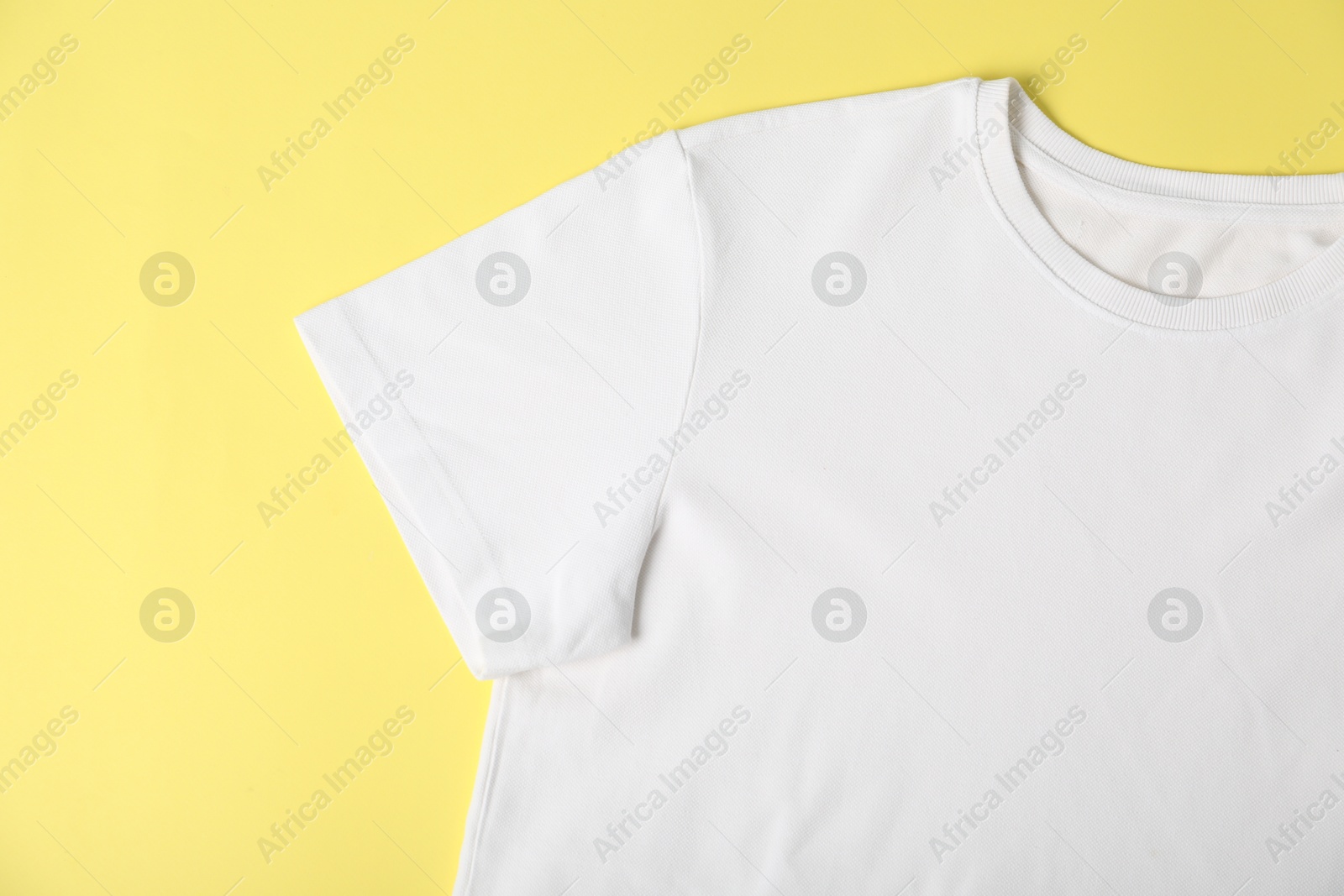 Photo of White t-shirt on yellow background, top view. Mockup for design