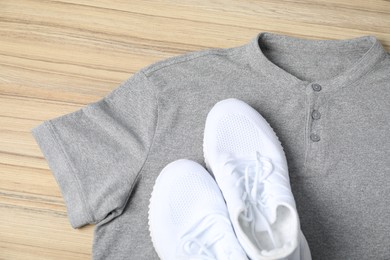 Photo of Grey t-shirt and sneakers on wooden table, top view. Mockup for design