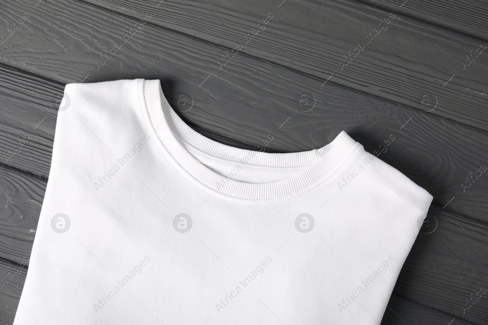Photo of White t-shirt on grey wooden table, top view. Mockup for design