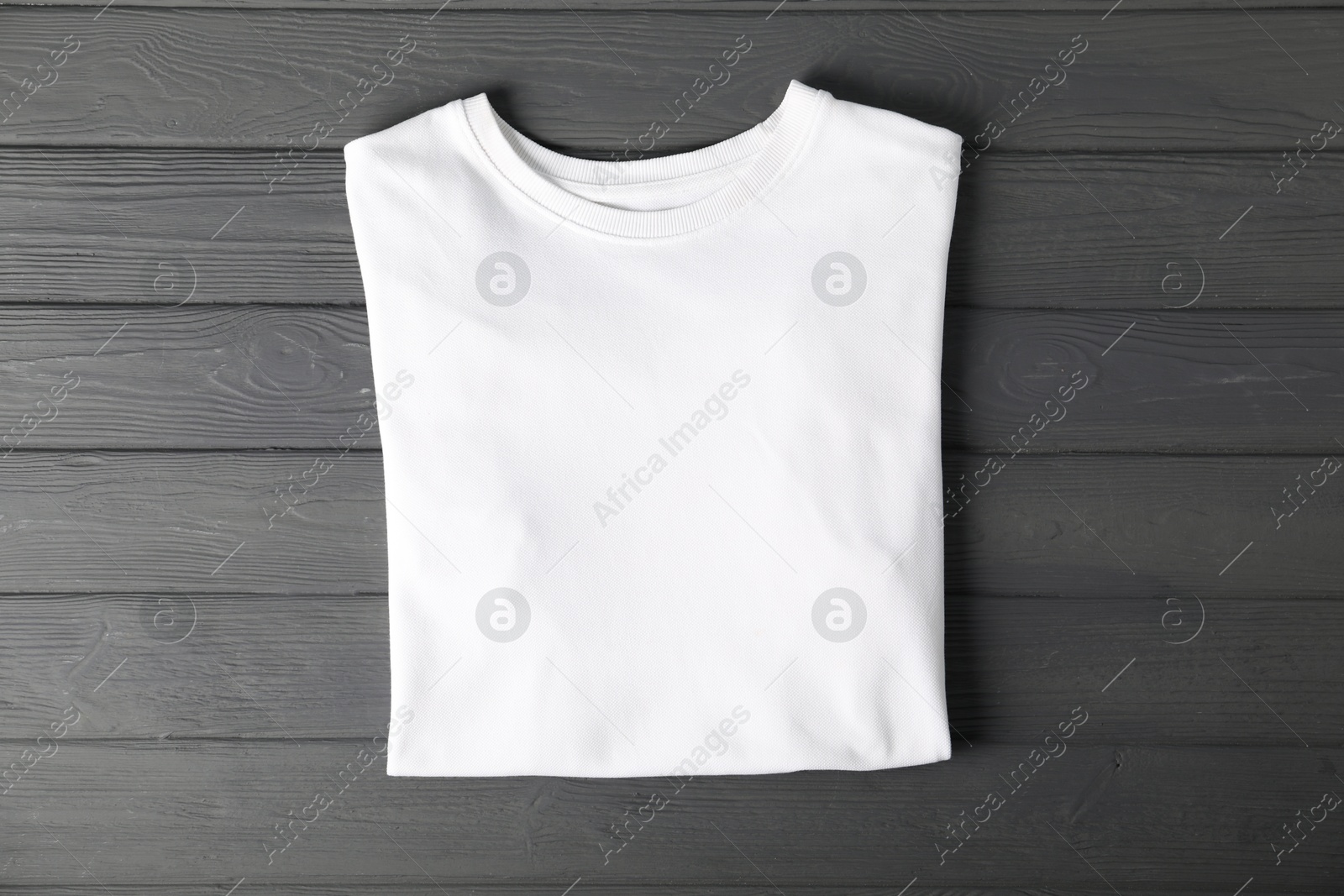 Photo of White t-shirt on grey wooden table, top view. Mockup for design