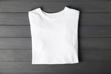 Photo of White t-shirt on grey wooden table, top view. Mockup for design