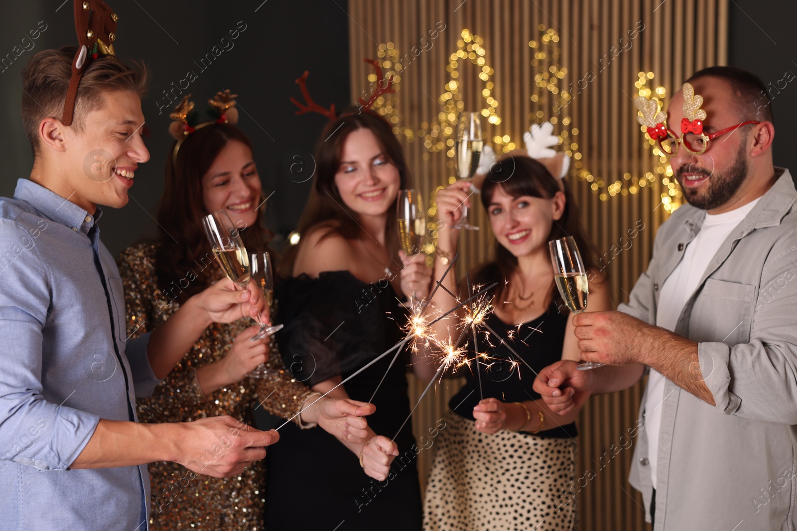 Photo of Friends celebrating New Year with sparklers and wine glasses indoors