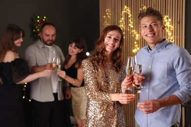 Photo of Friends celebrating New Year with sparklers and wine glasses indoors
