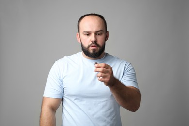 Photo of Baldness problem. Worried man with clump of lost hair on grey background