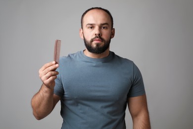 Photo of Baldness problem. Man with comb on grey background