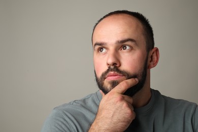 Photo of Baldness problem. Thoughtful man with receding hairline on grey background. Space for text