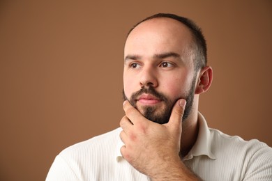 Photo of Baldness problem. Thoughtful man with receding hairline on brown background. Space for text