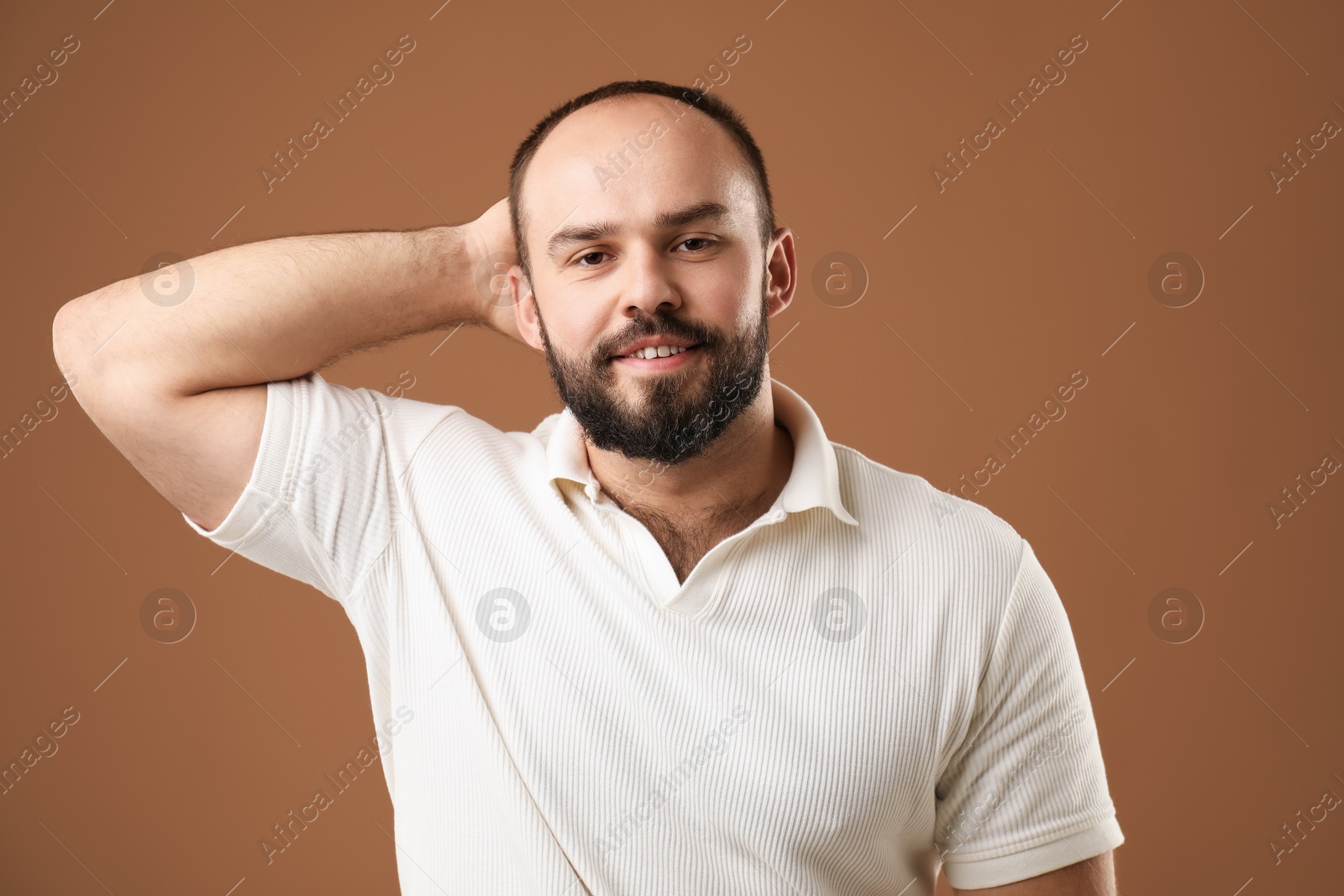 Photo of Baldness problem. Portrait of smiling man with receding hairline on brown background