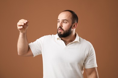 Photo of Baldness problem. Worried man with clump of lost hair on brown background