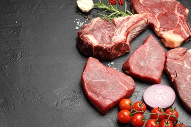 Photo of Pieces of raw beef meat, spices and tomatoes on black table, above view. Space for text