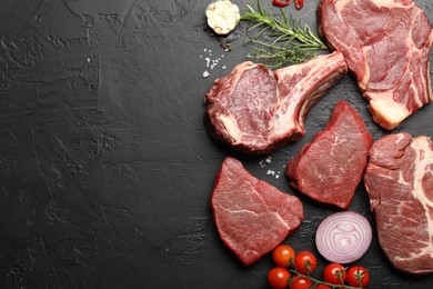 Photo of Pieces of raw beef meat, spices and tomatoes on black table, flat lay. Space for text
