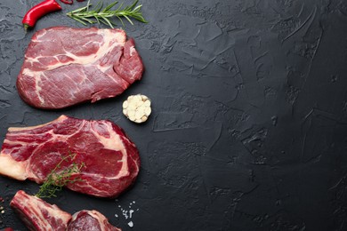 Photo of Pieces of raw beef meat and spices on black table, flat lay. Space for text