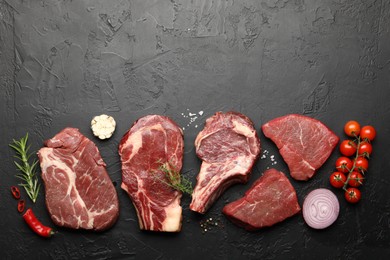 Photo of Pieces of raw beef meat, spices and tomatoes on black table, flat lay. Space for text