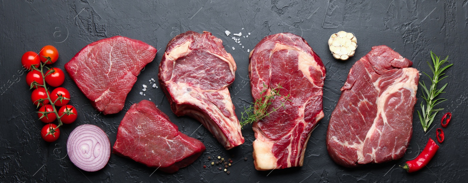 Photo of Pieces of raw beef meat, spices and tomatoes on black table, flat lay