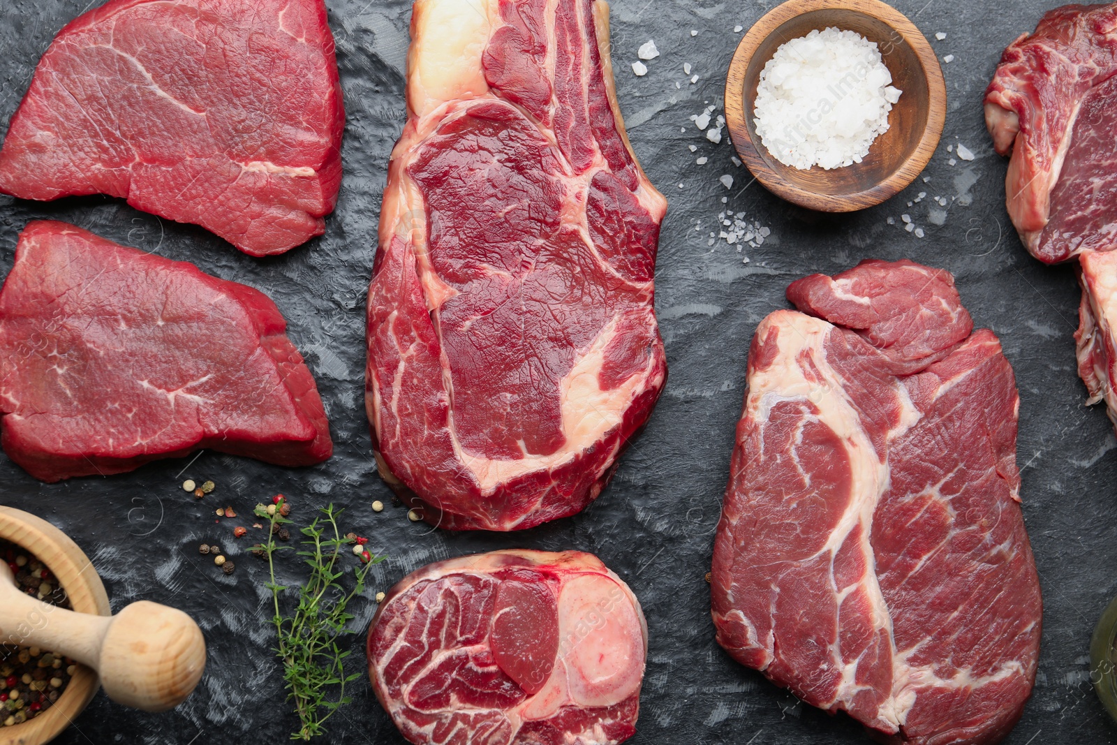 Pieces of raw beef meat and spices on black marble table, flat lay Photo of Pieces of raw beef meat and spices on black marble table, flat lay
