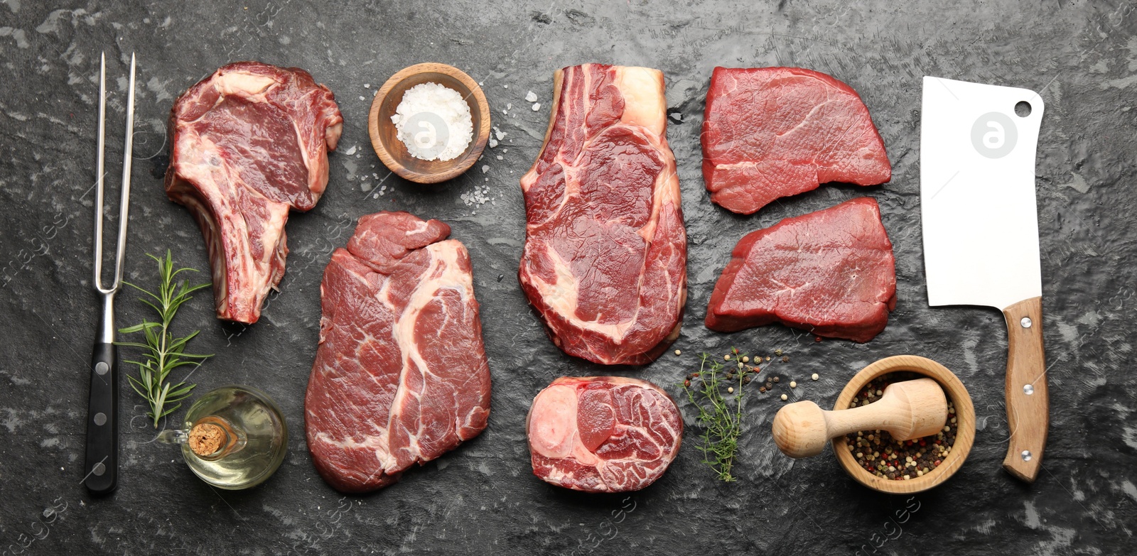 Photo of Pieces of raw beef meat, spices, carving fork and cleaver on black marble table, flat lay